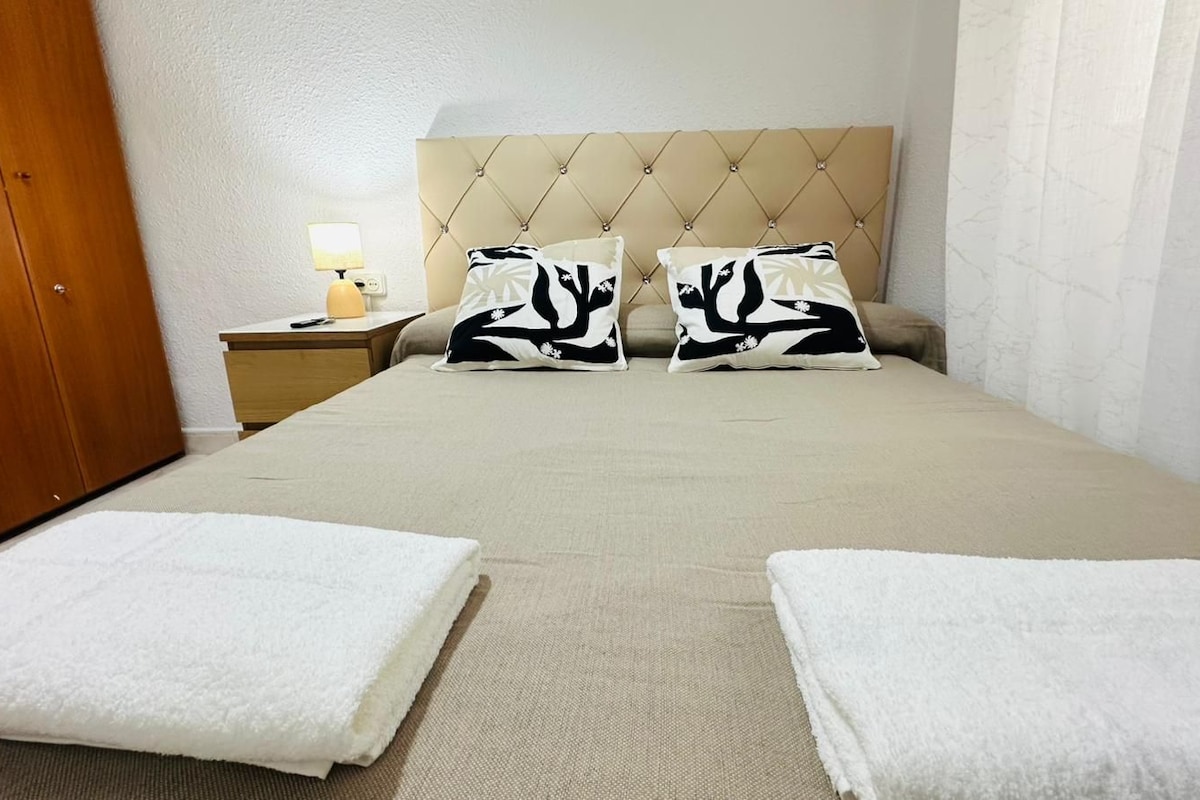 Una habitación de hotel con una cama, dos almohadas, una mesita de noche con lámpara y dos toallas.