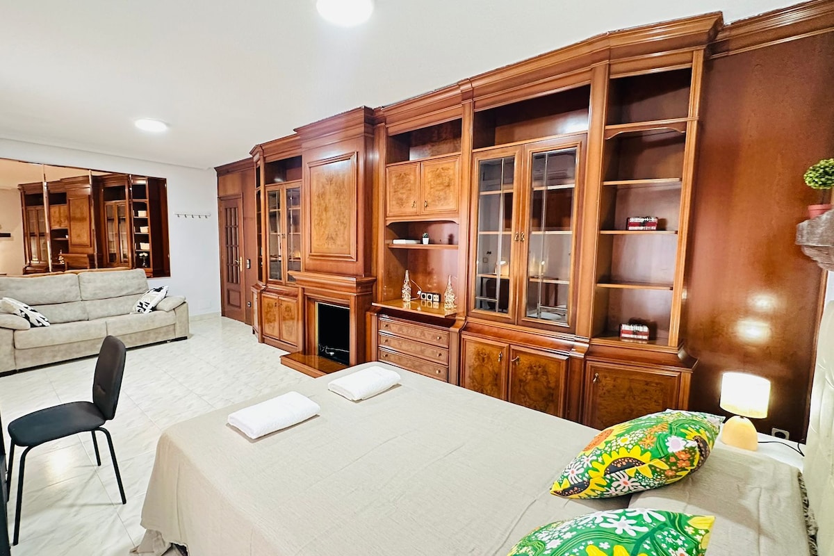 Una habitación de hotel con una cama, un sofá, un escritorio y un armario de madera grande.