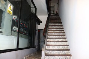 Eine Treppe mit gemusterten Fliesen führt zu einem Raum mit einem großen Fenster und elektrischen Schaltfeldern.
