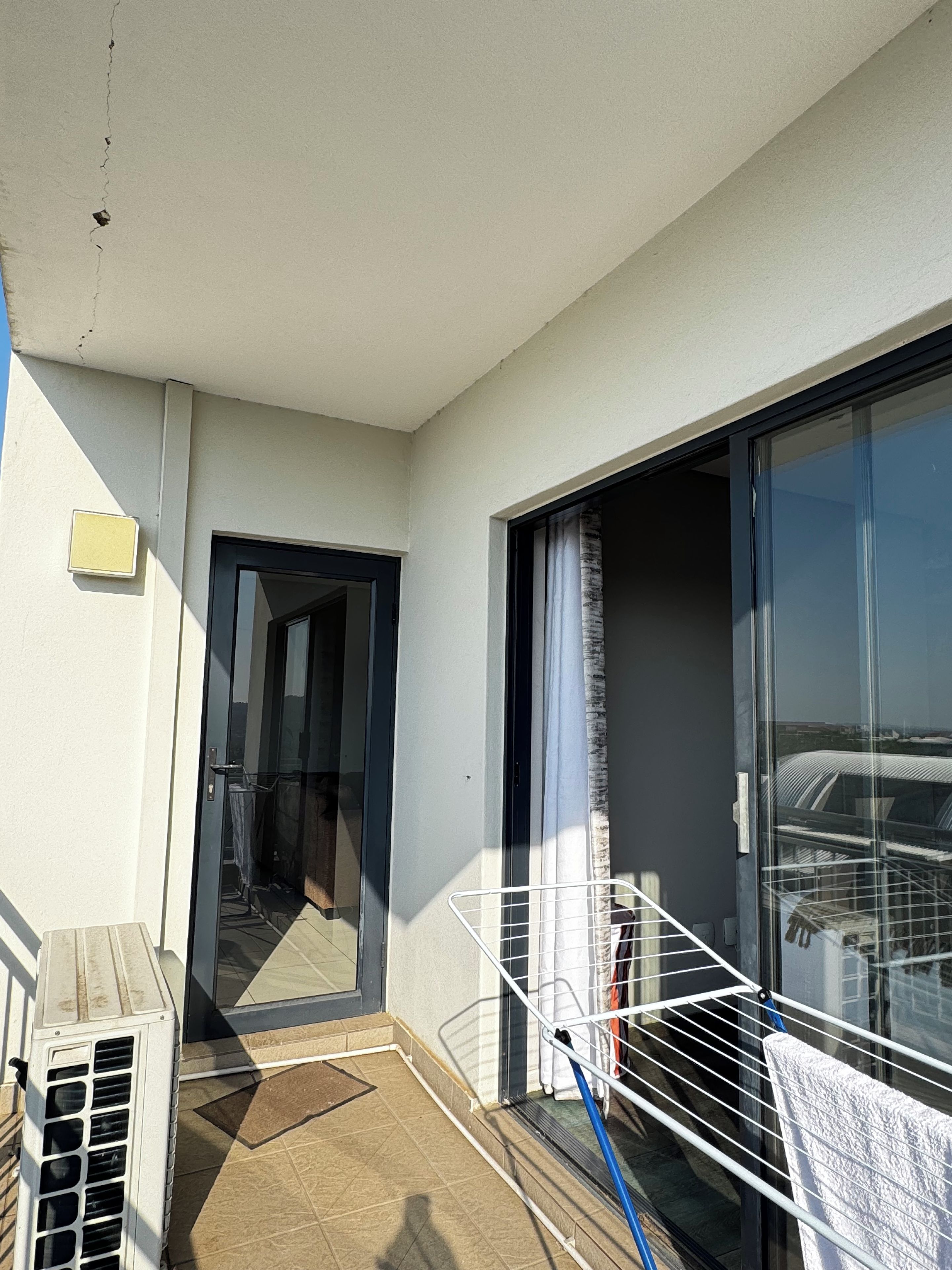 A balcony with a clothes drying rack, a door leading to an interior space, and a view of the cityscape.