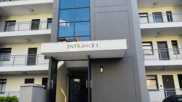 A modern building with a prominent entrance labeled 'Entrance 1,' featuring a staircase leading up to the door.