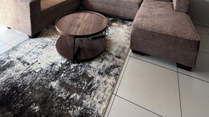 A modern living room with a sectional sofa, a round coffee table, and a patterned rug. - Apartment in Sandton (Sandton)
