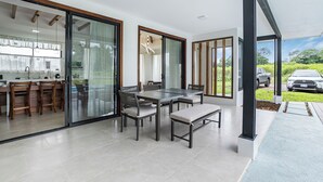 Una cocina moderna con comedor, amplios ventanales correderos y un coche visible al fondo.