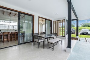 Una cocina moderna con comedor, amplios ventanales correderos y un coche visible al fondo.
