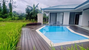 Una casa moderna con piscina, rodeada de exuberante vegetación.