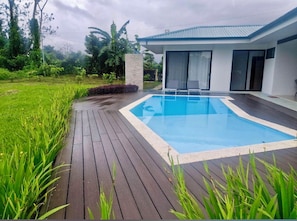 Una casa moderna con piscina, rodeada de exuberante vegetación.