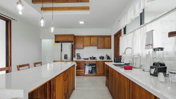 Una cocina moderna con armarios de madera, una isla central y un comedor con sillas.