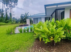 Una casa moderna con piscina, rodeada de vegetación exuberante y un césped cuidado.