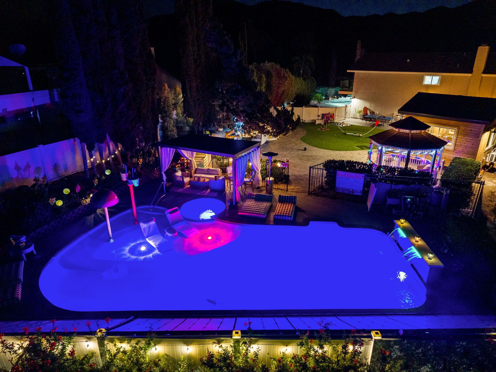 Ein Außenpool-Bereich bei Nacht mit überdachter Sitzgelegenheit und einem Pavillon.