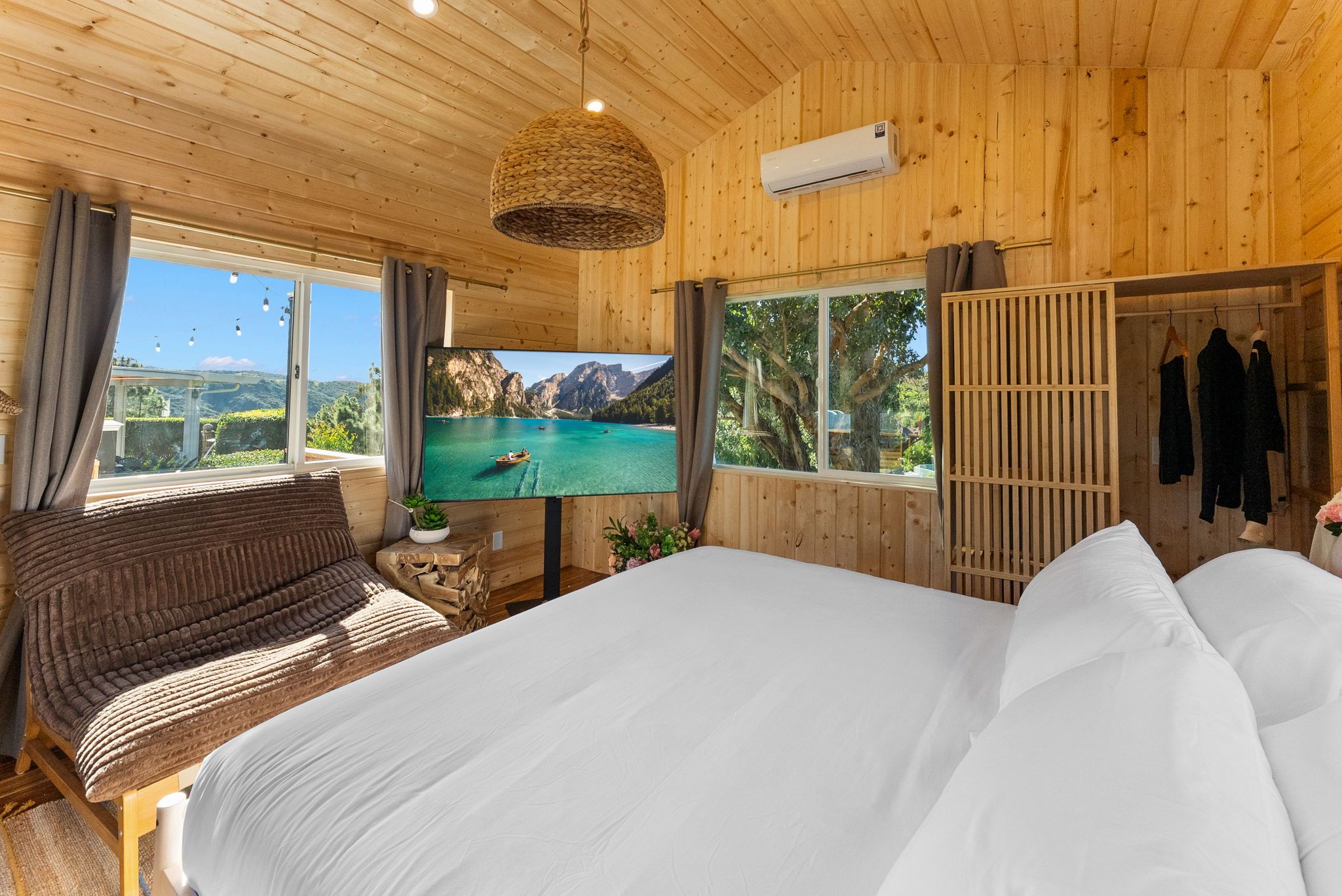 A wooden room with a bed, a sofa, a TV, and a wardrobe.