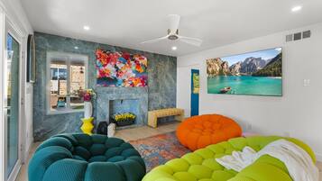A modern living room with a fireplace, colorful artwork, and a large window.