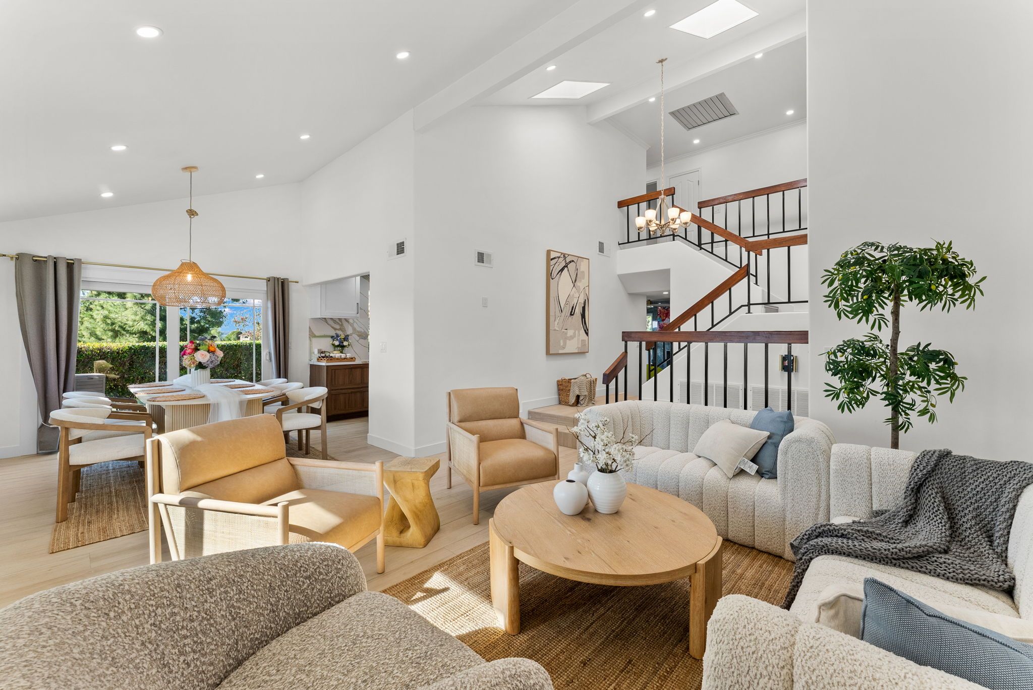A spacious living area with a staircase, modern furniture, and a view of the outdoors.