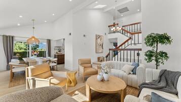A spacious living area with a staircase, modern furniture, and a view of the outdoors.