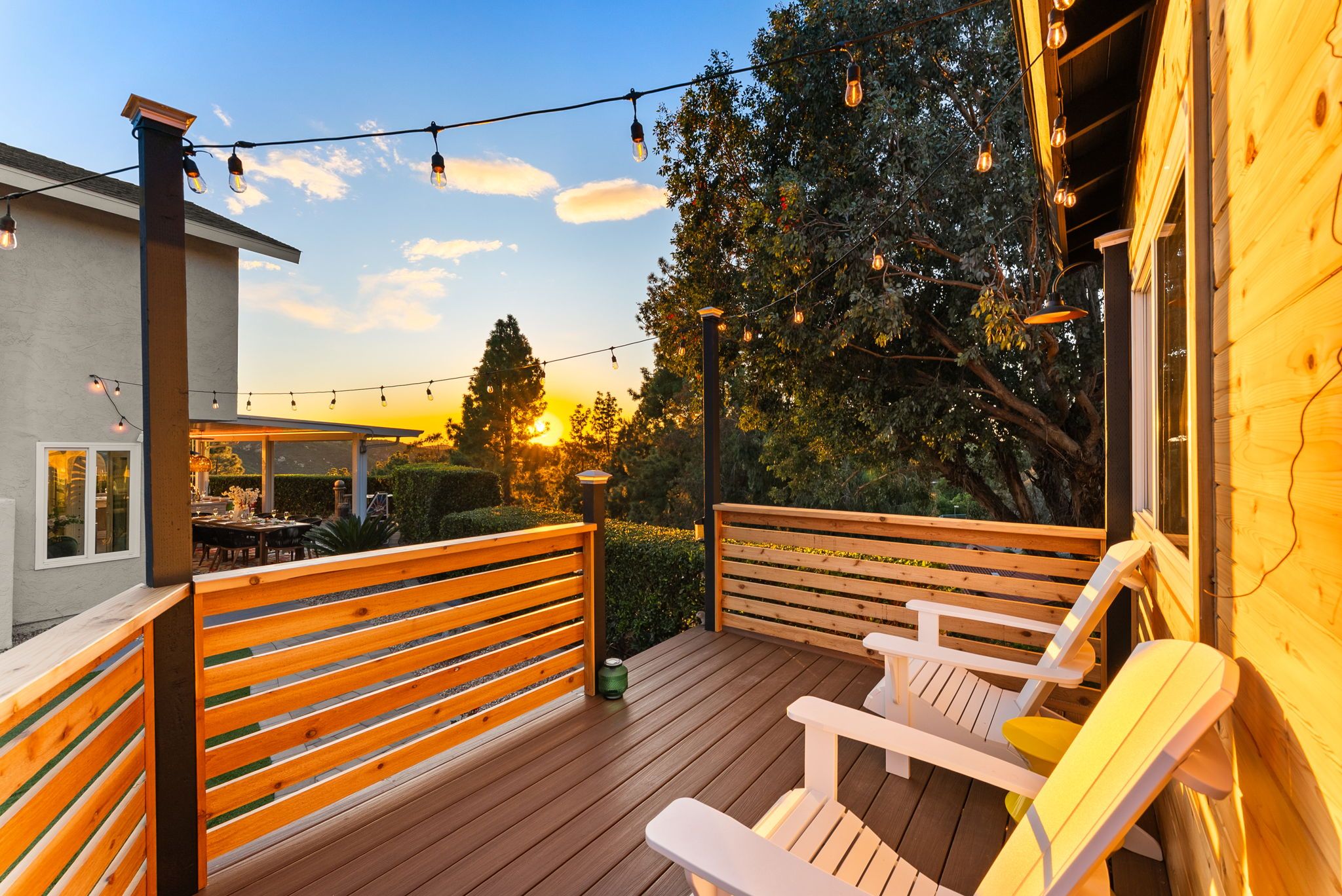 An outdoor deck with wooden railings, a covered seating area, and string lights.