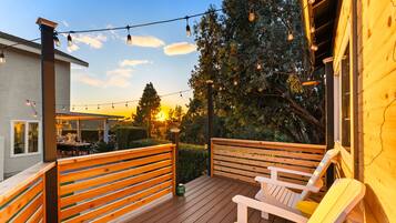 An outdoor deck with wooden railings, a covered seating area, and string lights.