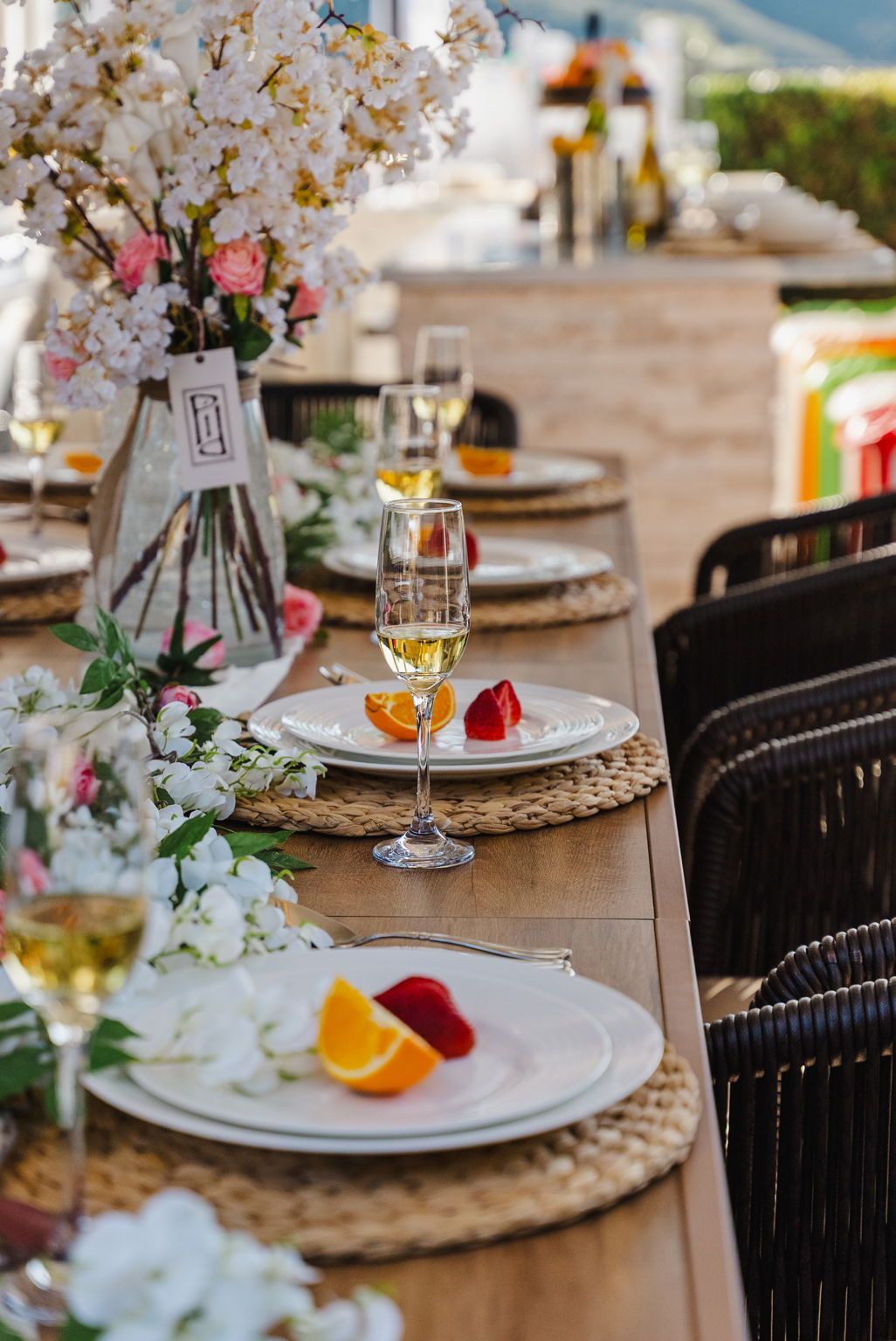 A dining table set with plates, glasses, and a vase of flowers.