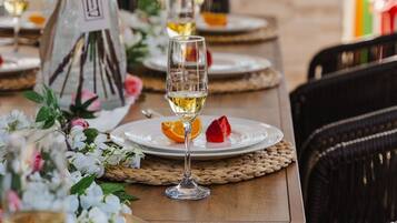 A dining table set with plates, glasses, and a vase of flowers.