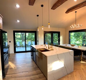 A modern kitchen with a marble island, pendant lighting, and a view of the outdoors.
