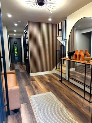 Un interno moderno con pavimento in legno, un divano nero, un tappeto decorato e una scala con ringhiera nera.