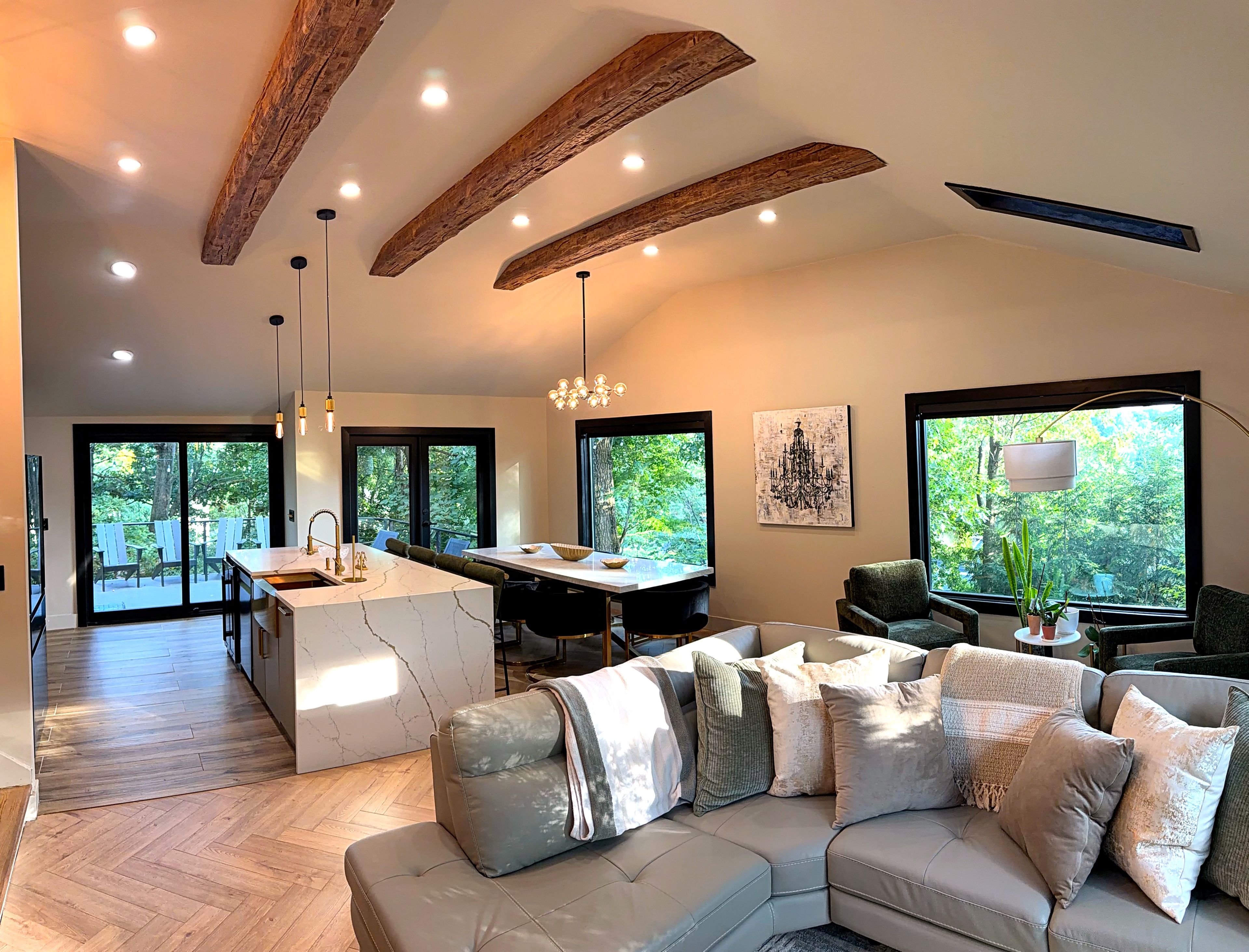 A spacious living area with a large sofa, a dining table, and a kitchen with a marble island.