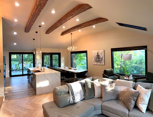 A spacious living area with a large sofa, a dining table, and a kitchen with a marble island.