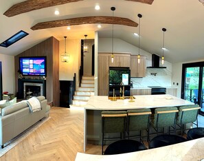 A modern kitchen with a central island, bar stools, and pendant lighting.