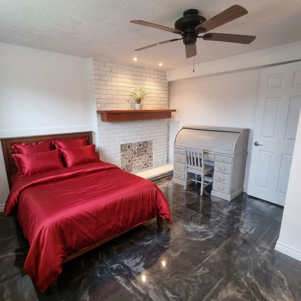 A bedroom with a bed, a desk, a ceiling fan, a fireplace, and a door.