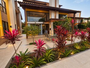 A modern house with a patio area featuring a dining table and chairs, surrounded by a variety of plants. - Bahia Beira Mar Hotel (Porto Seguro)