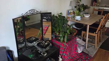 Un salon comprenant un canapé, une table basse recouverte d’une nappe à carreaux rouges, un miroir et un coin repas avec une table et des chaises en bois.