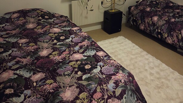 A bedroom with two beds, a window with a curtain, a potted plant, and a radiator. - Luxury Apartment - The subway is right outside the apartment (Stockholms län)