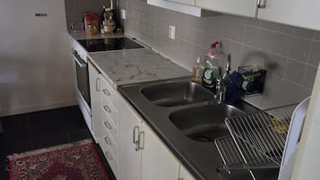 Una cocina con gabinetes blancos, un lavamanos doble y una estufa.