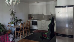 A modern kitchen with white cabinets, a stainless steel refrigerator, and a dining area with a wooden table and chairs. - Luxury Apartment - The subway is right outside the apartment (Stockholms län)