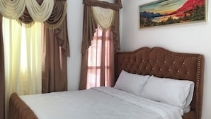 A bedroom with a large bed, curtains, and a painting on the wall. - Superhost Home - 2 min Airport -Pool WiFi - Samal (Davao)