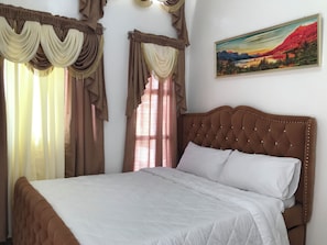 Une chambre à coucher avec un grand lit, des rideaux et un tableau au mur.