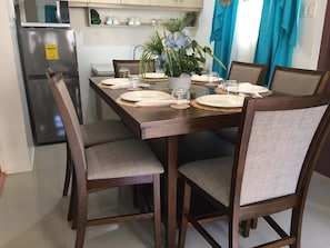 Une table à manger dressée avec des assiettes, des verres et un vase de fleurs, entourée de chaises.