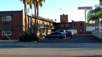 A motel with a sign, parked cars, and palm trees.