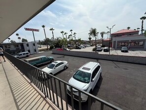 A motel with a parking lot, several parked cars, and a building with a red roof.