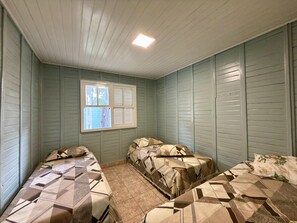 Una habitación con dos camas, una ventana y una lámpara en el techo.