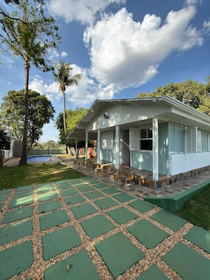 Une maison dotée d’un porche abrité, d’une piscine et d’un chemin pavé.