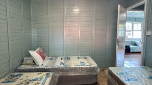 A room with two beds, a tiled floor, and a door leading to another room. - Country house with sand court and heated pool. (Americana)