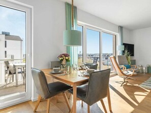 Ein stilvoller Essbereich mit Tisch für zwei, Blick auf die Stadt und ein Balkon mit Sitzgelegenheit im Freien.