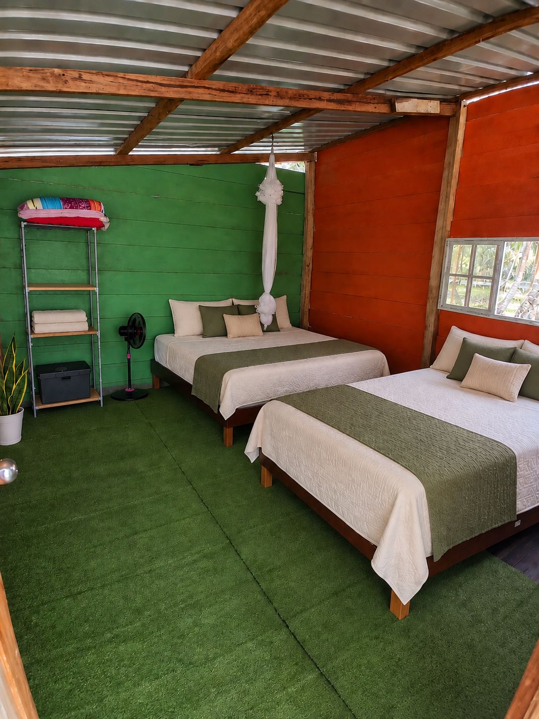 Una habitación con dos camas, una pared verde y una pared roja, además de un ventanal.