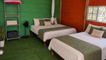 Una habitación con dos camas, una pared verde y una pared roja, además de un ventanal.