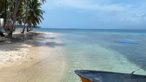 A beach with clear water, a sandy shore, and a boat. - cabaña madera sanblas luxury  (Nusatupo)