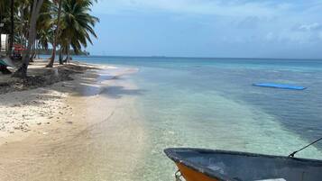 Una playa con agua cristalina, orilla de arena y un bote.