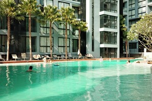 Ein Swimmingpool mit klarem Wasser, umgeben von Palmen und Liegestühlen.
