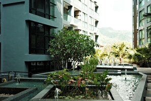 A modern building with a water feature and lush greenery in front. - Kamala - Peaceful Jungle View (Kathu District)