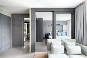 Ein modernes Hotelzimmer mit einer Couch, einem Bett und einem durch eine offene Tür einsehbaren Badezimmer.