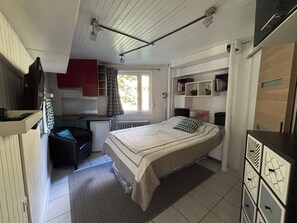 Ein gemütliches Schlafzimmer mit einem Bett, einem Schreibtisch, einem Stuhl und einer Heizung.