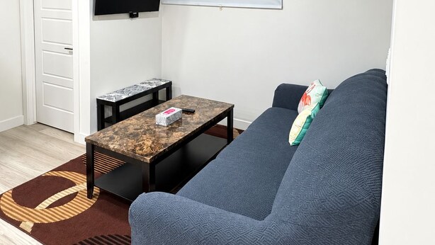 Ein Wohnzimmer mit einer Couch, einem Couchtisch, einem Flachbildfernseher und einer Whiteboard-Tafel.